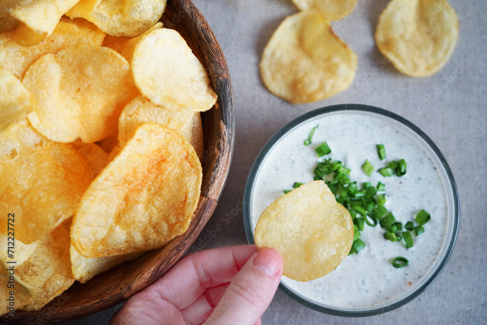 Potato chips with sauce with herbs on a gray background Potato chips with sauce with herbs on a gray background