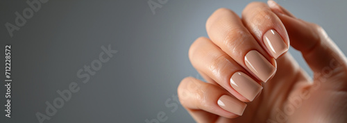 Woman hand with nude nail polish on her fingernails. Manicure concept. photo