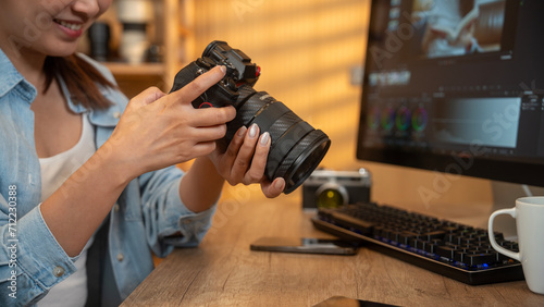 Close up of photographer woman hands with laptop checking dslr camera on a desk at home