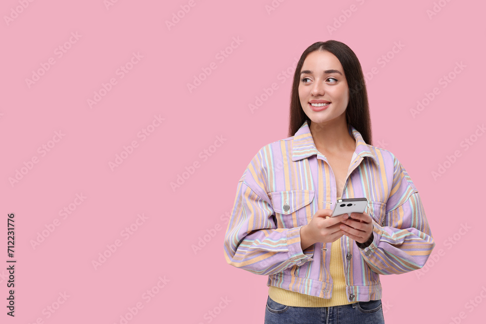 Happy woman sending message via smartphone on pink background, space for text Happy woman sending message via smartphone on pink background, space for text