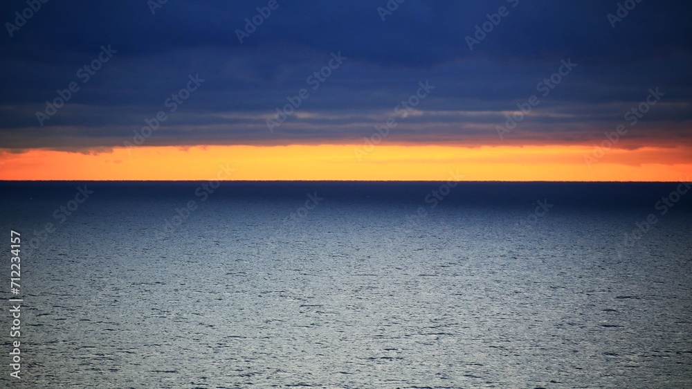 Orange horizon between dark clouds and Baltic sea