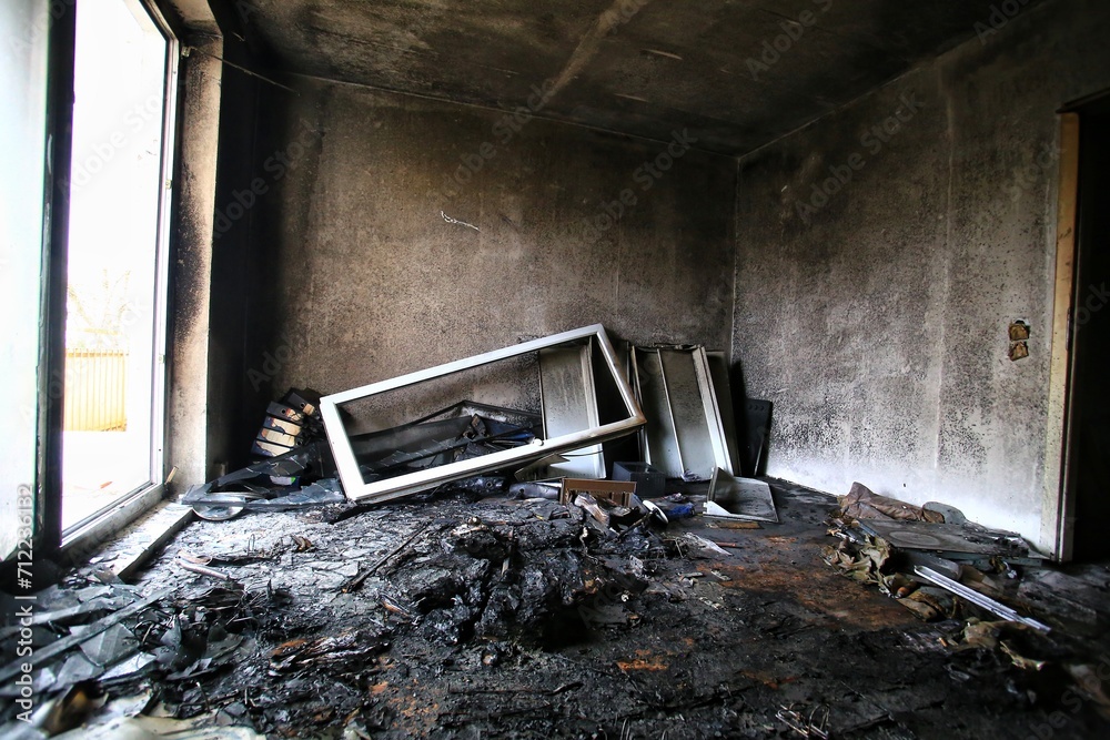 Burnt and destroyed room with bright daylight coming from balcony door