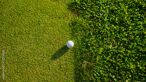 Golf ball on green grass in the evening golf course with sunshine background.