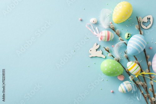 Step into spring with top view capturing essence of Easter—colorful eggs, charming bunny, pussy willow blossoms, sugar sprinkles, pastel blue background, offering ideal canvas for your text or promo