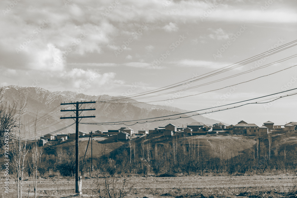 Fototapeta premium a beautiful Village on the top of the mountain and empty field with the electric wire going through