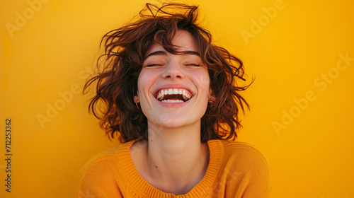 Portrait of a cheerful woman in front of a vibrant yellow background, happy and joyful expression