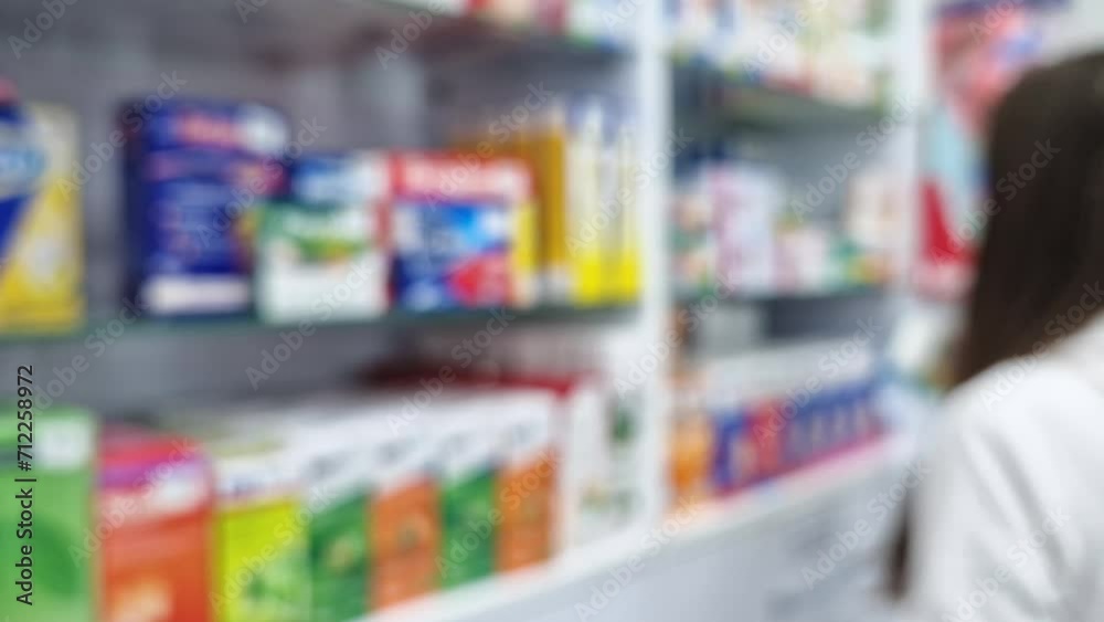 Defocus view inside of pharmacy with female pharmacist arranging drugs on the shelves. Healthcare and cosmetics industry blurred background Defocus view inside of pharmacy with female pharmacist arranging drugs on the shelves. Healthcare and cosmetics industry blurred background