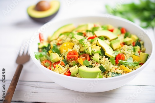 couscous salad in a white bowl with avocado slices