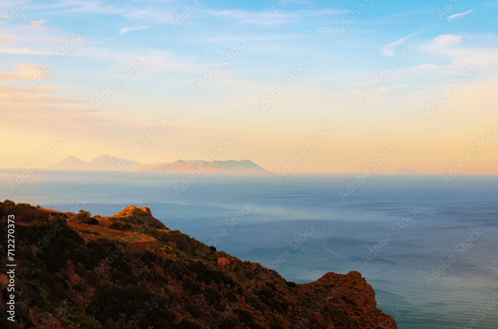 Picturesque aerial sunset seascape of Mediterranean Sea near Tindari, Sicily. Mountains in haze on horizon, colorful vibrant sky. Travel and tourism concept