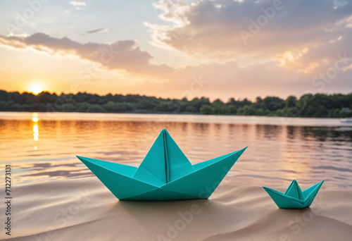 Hand holding origami ship with paper boats on river at sunset photo