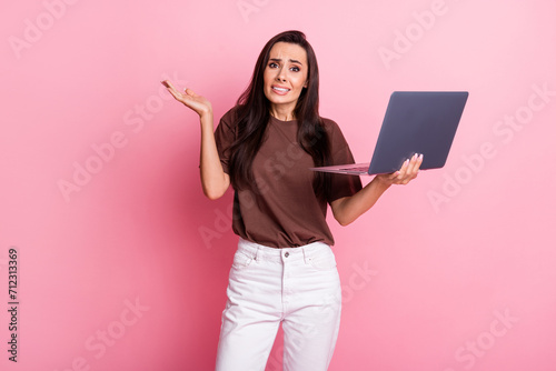 Photo of young stressed woman too busy for all job in office bring netbook shrug shoulders miss calls isolated on pink color background photo