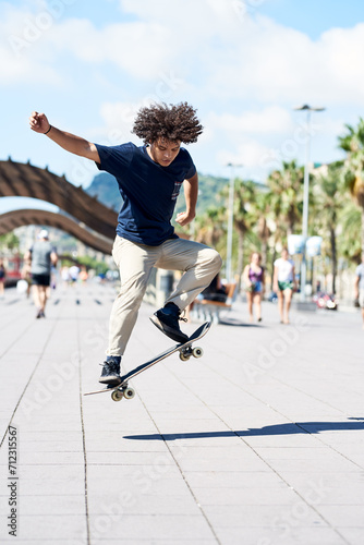 Teen boy performing trick on sunny street.