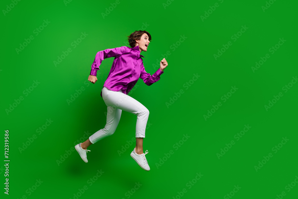 Full size profile photo of energetic excited girl jump rush empty space offer ad isolated on green color background