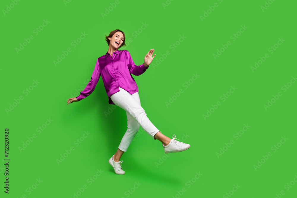 Full length photo of cheerful good mood lady dressed trendy bright clothes walking store empty space isolated on green color background