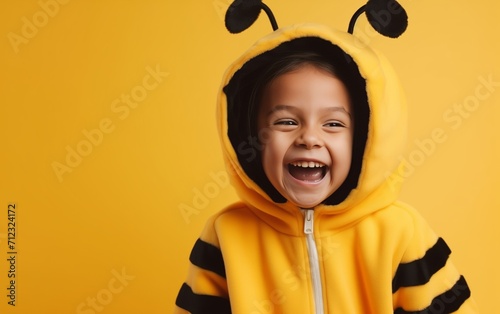 child in a bee costume, smiling, on a light yellow background, space for text 