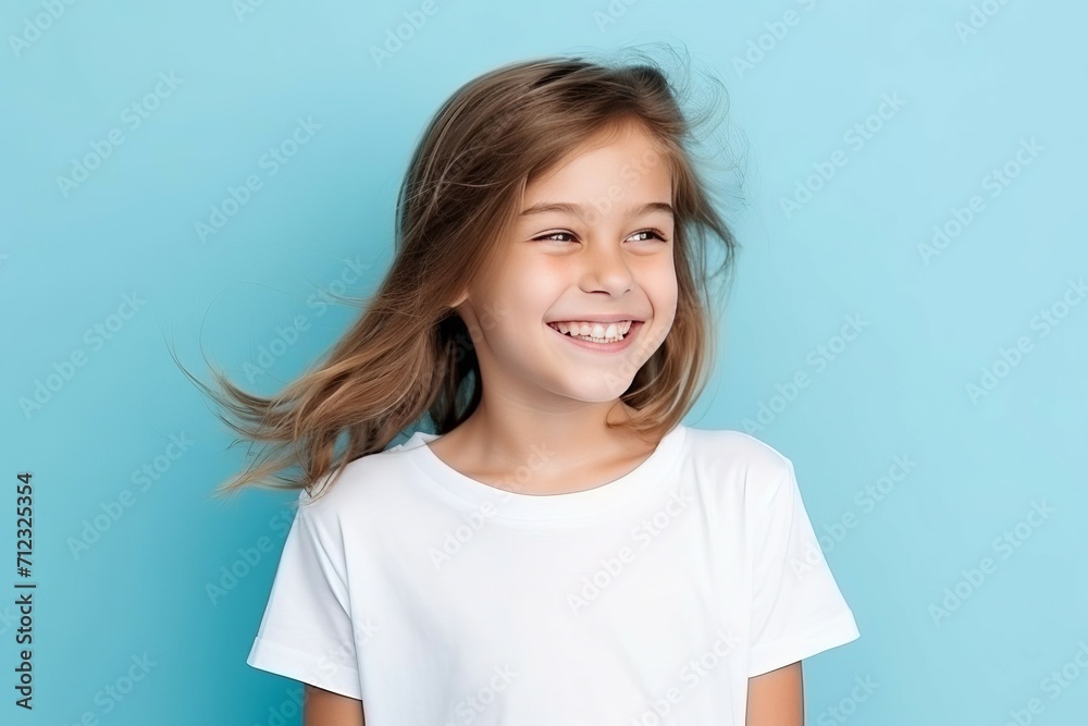 Portrait of a pretty smiling 7-year-old girl in a white T-shirt on a blue background, copy space. Happy child, childhood Portrait of a pretty smiling 7-year-old girl in a white T-shirt on a blue background, copy space. Happy child, childhood