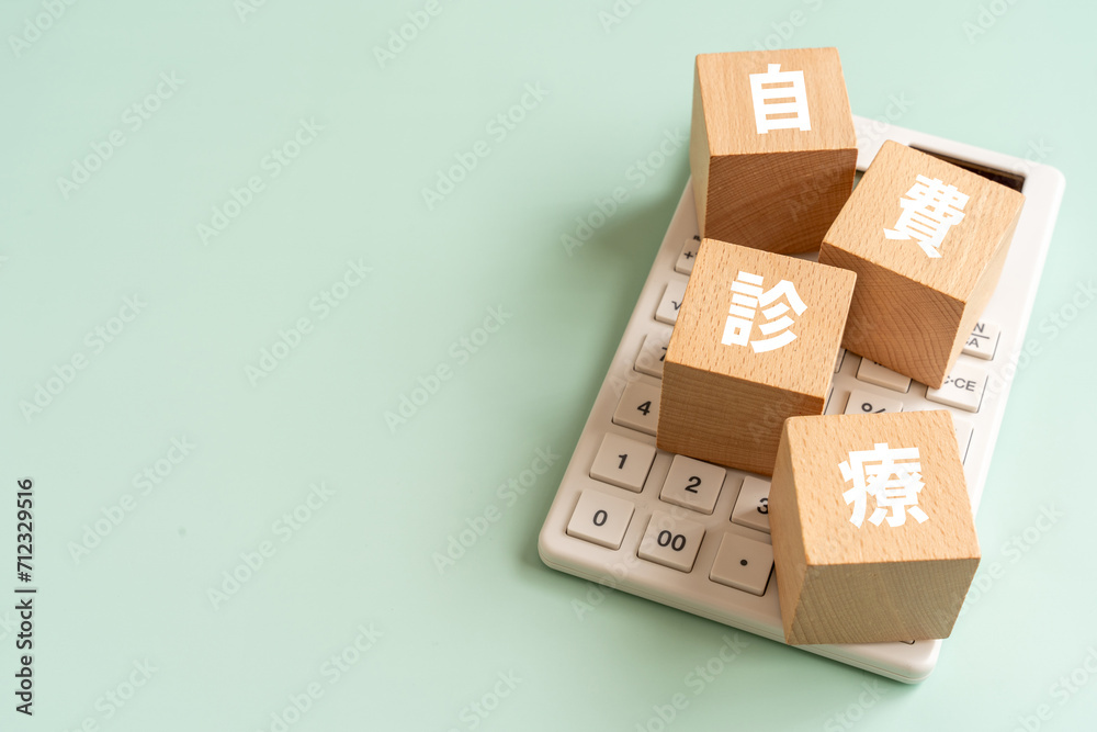 自費診療の文字が入ったブロックと電卓 自費診療の文字が入ったブロックと電卓