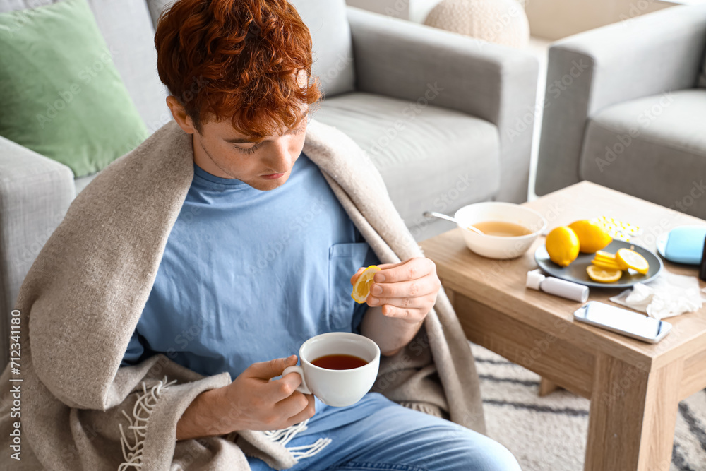 Ill young man drinking tea with lemon at home Ill young man drinking tea with lemon at home