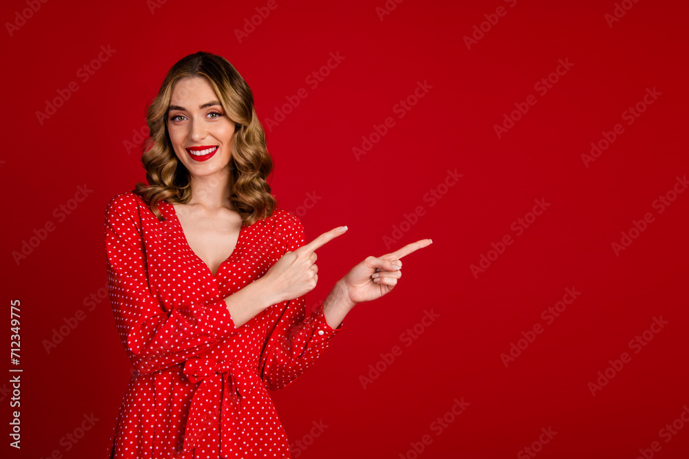 Photo of pretty cheerful lady direct fingers empty space event information isolated on red color background Photo of pretty cheerful lady direct fingers empty space event information isolated on red color background