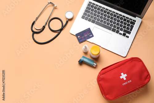 Laptop, credit card and first aid kit on beige background