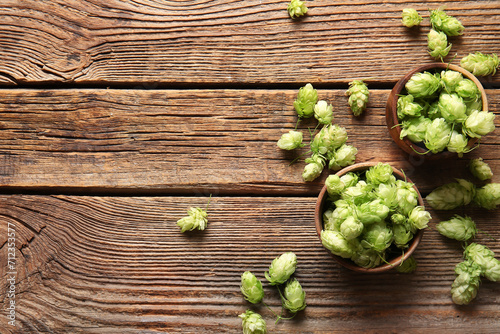 Bowls with fresh green hops on wooden background