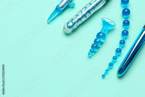 Different anal plugs and vibrators from sex shop on turquoise background