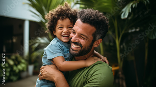 Homem brasileiro vestindo roupas verdes abraçando seu filho e sorrindo  photo
