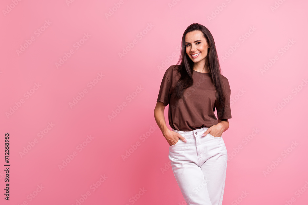Photo of gorgeous satisfied lady put arms pockets toothy smile empty space ad isolated on pink color background Photo of gorgeous satisfied lady put arms pockets toothy smile empty space ad isolated on pink color background