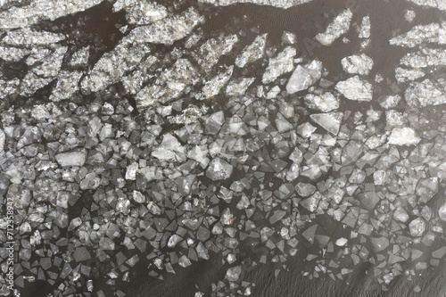 The texture of a frozen lake and pieces of floating ice in the water. Winter landscape from a drone.
