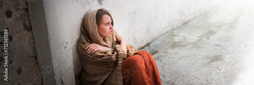 A girl in poor clothes sits on the ground