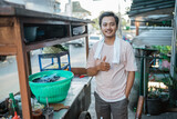 asian seller standing behind traditional food cart with thumb up gesture