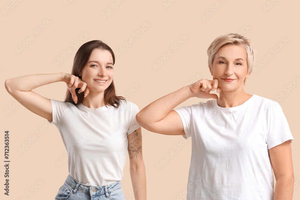 Beautiful women doing face building exercise on beige background Beautiful women doing face building exercise on beige background