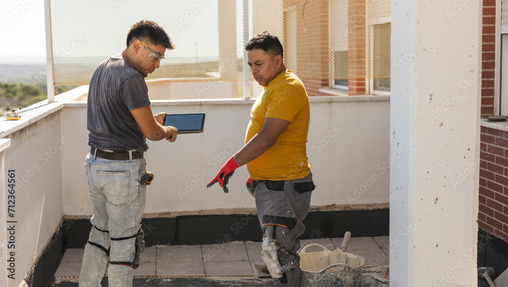 worker on the terrace putting asphalt cloth, they have a digital tablet