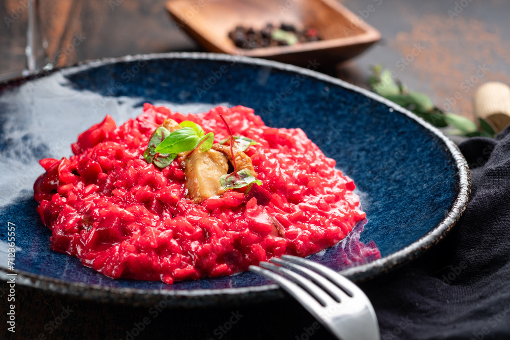 Risotto with beetroot and mushrooms in a blue plate on a wooden background, close up Risotto with beetroot and mushrooms in a blue plate on a wooden background, close up
