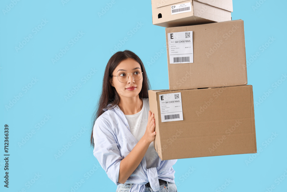 Young Asian seller with parcels on blue background Young Asian seller with parcels on blue background