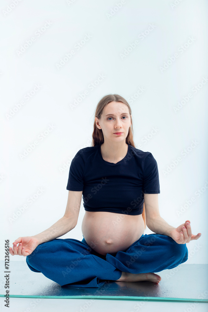 Pleasant pregnant woman posing in profile and trying yoga Young happy expectant relaxing, thinking about her baby and enjoying her future life. Motherhood, pregnancy, yoga concept, lotus position. Pleasant pregnant woman posing in profile and trying yoga Young happy expectant relaxing, thinking about her baby and enjoying her future life. Motherhood, pregnancy, yoga concept, lotus position.