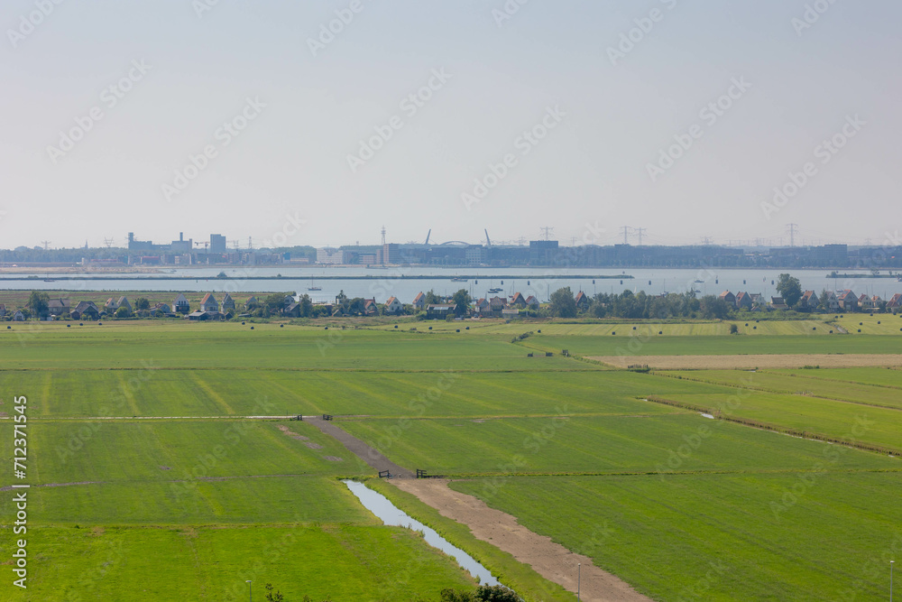 Fototapeta premium Typical Dutch polder in summer, Canal or ditch and green meadow, Overview from the top of Church tower in Ransdorp, A small village part of the municipality of Amsterdam, North Holland, Netherlands.