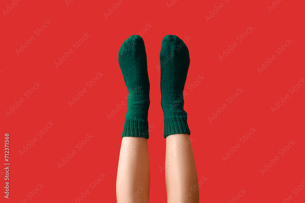 Legs of young woman in warm green knitted socks on red background Legs of young woman in warm green knitted socks on red background