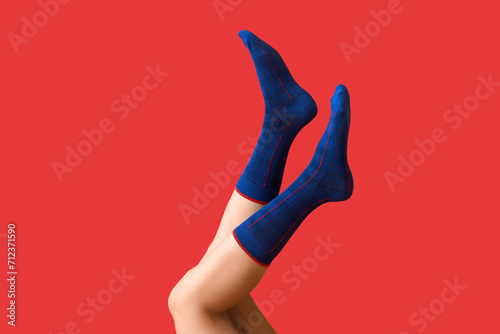 Legs of young woman in blue socks on red background