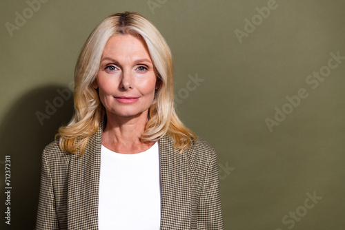 Photo portrait of mature age confident woman blonde hair team leader in formal jacket business style isolated over khaki color background