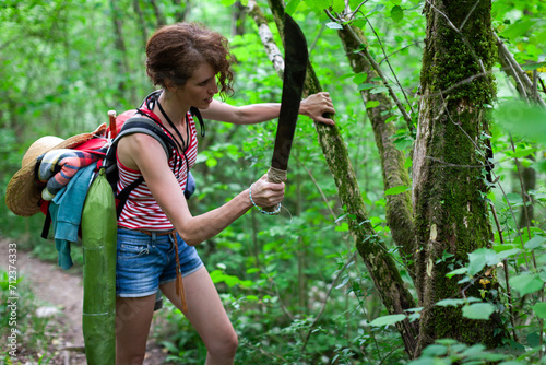 Gritty Survivalist Female Hiker Cleaning a Parasite Plant from a Tree on a Footpath in Woods