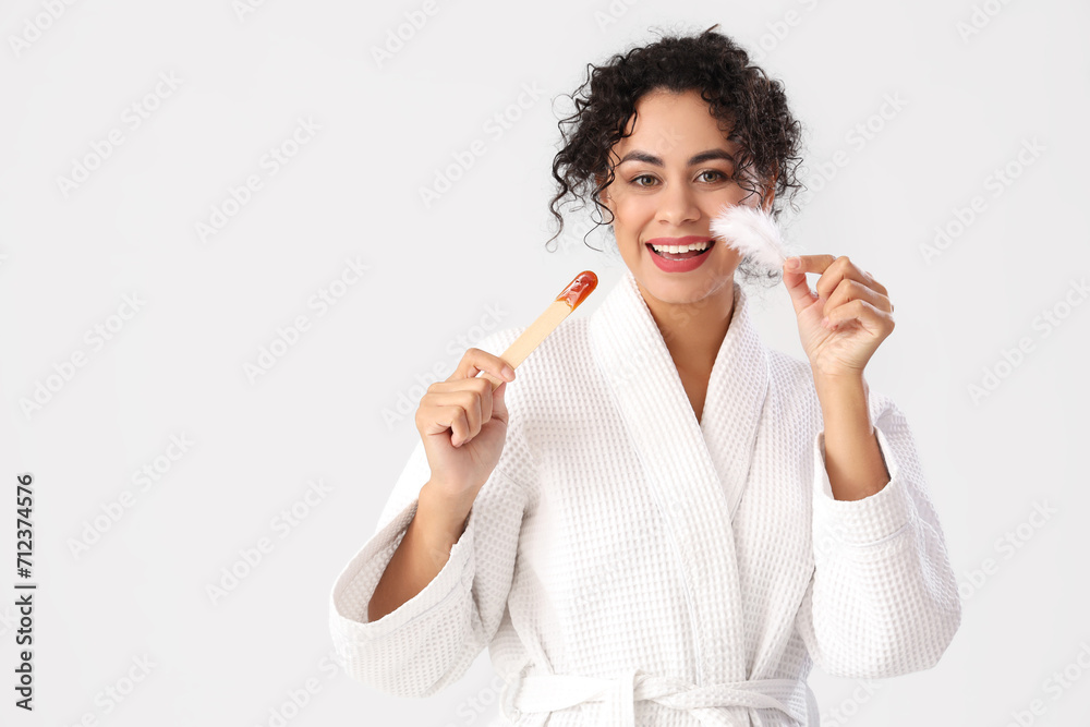 Beautiful African-American woman with sugaring paste and feather on white background Beautiful African-American woman with sugaring paste and feather on white background