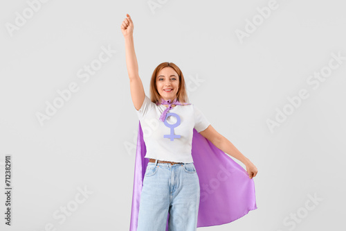 Mature woman dressed as superhero on light background
