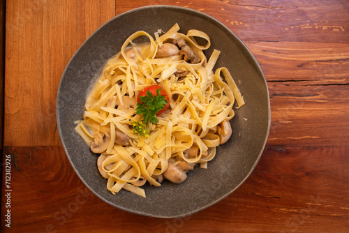 pasta with mushrooms in rustic plate on wooden table top view