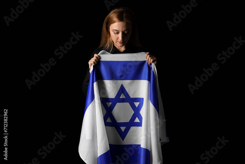 Mature woman with flag of Israel praying on black background. International Holocaust Remembrance Day photo