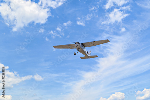 Single engine ultralight plane flying in the blue sky with white clouds