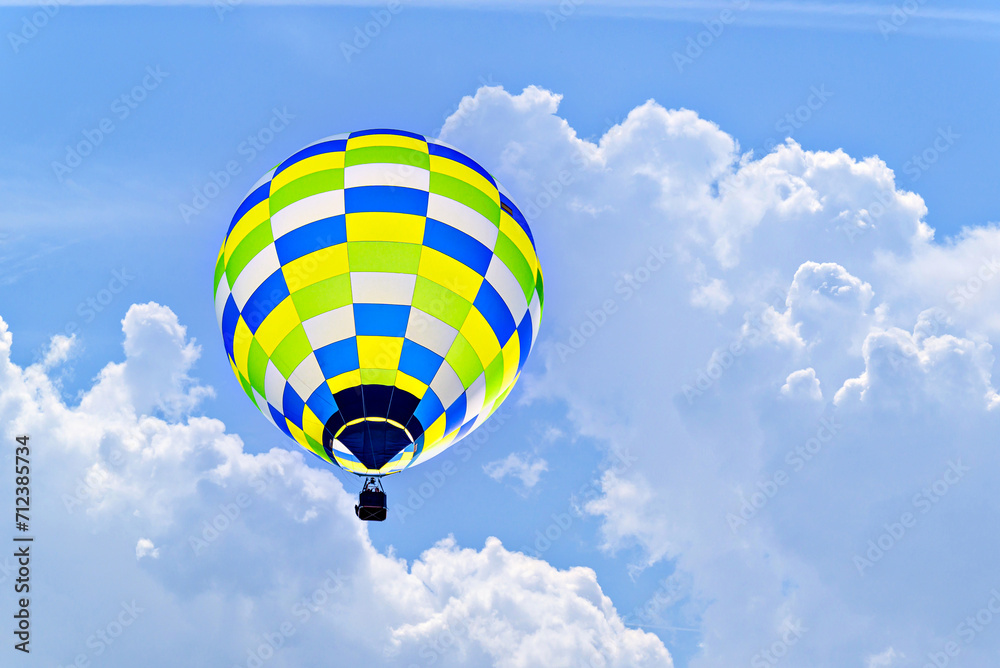 Fototapeta premium Colorful hot air balloon flying over blue sky with white clouds