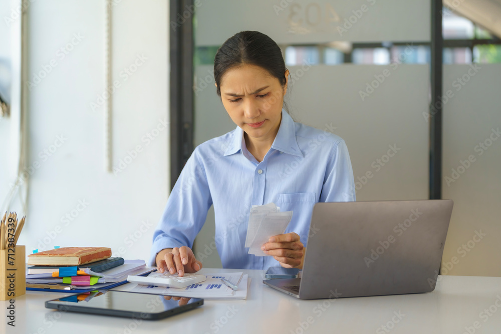 An Asian businesswoman is stressed over her expense bill. An Asian businesswoman is stressed over her expense bill.