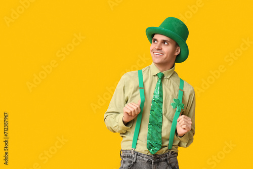 Happy young man in leprechaun's hat on yellow background. St. Patrick's Day