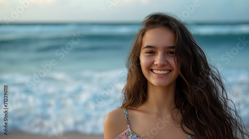 Lida mulher com cabelo marrom sorrindo na praia com o mar no fundo em um dia ensolarado photo